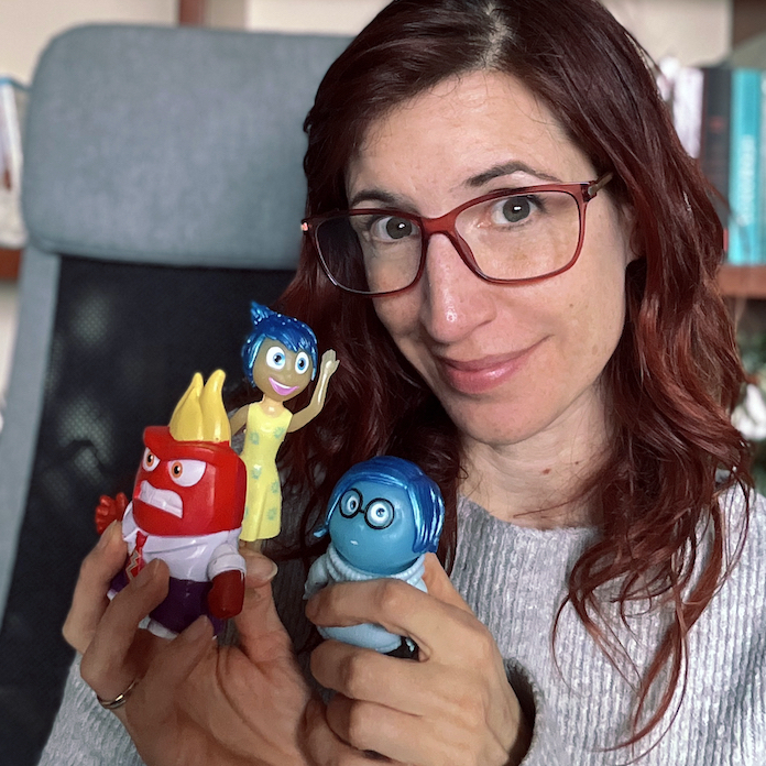 retrato de Ana del Valle sosteniendo diferentes figuras que representan las emociones en las manos